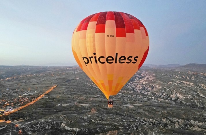 Hot air balloon with a priceless logo on it flying over Cappadocia